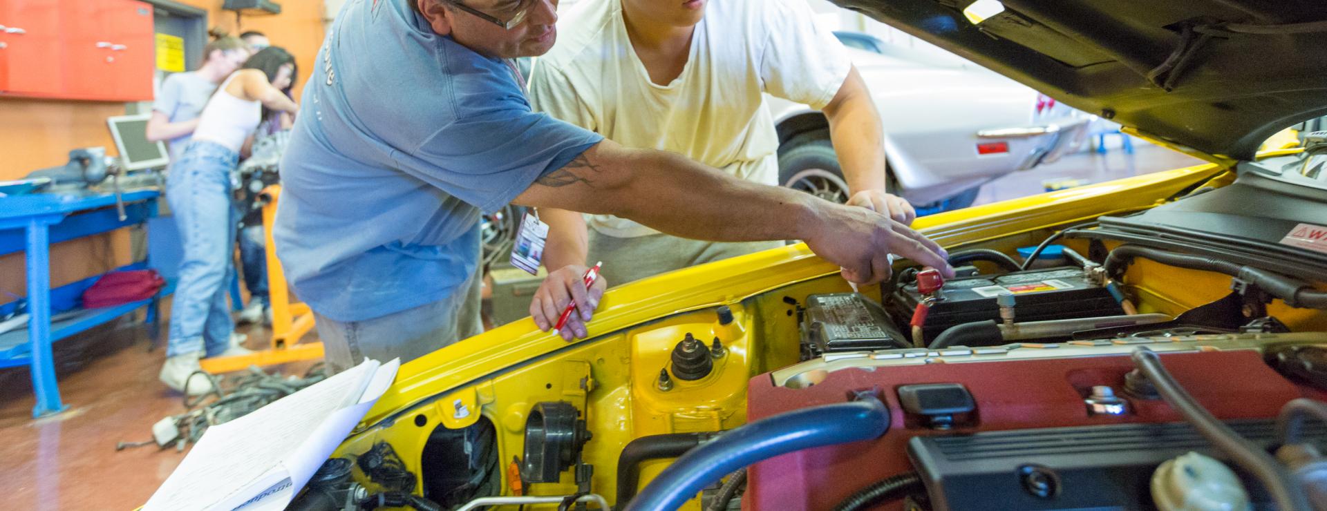 Auto Tech instructor showing student how to check car battery