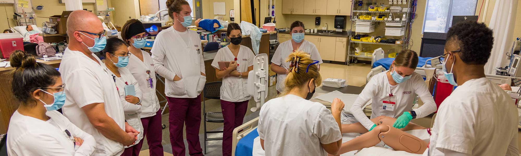 Nursing students practicing rounds using simulated patient to check vitals