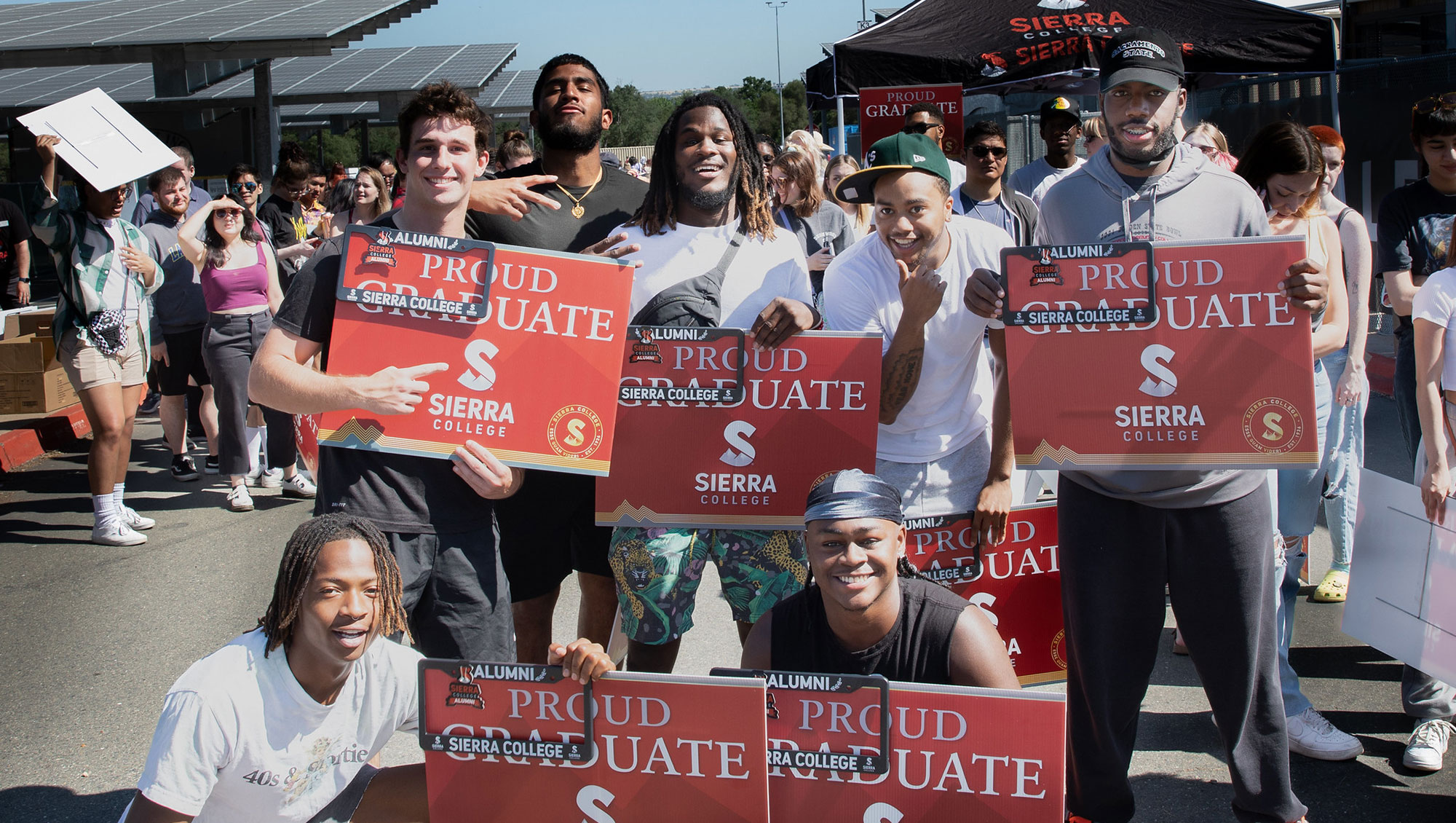 Sierra College graduates holding Proud Graduate signs at commencement practice on Rocklin Campus