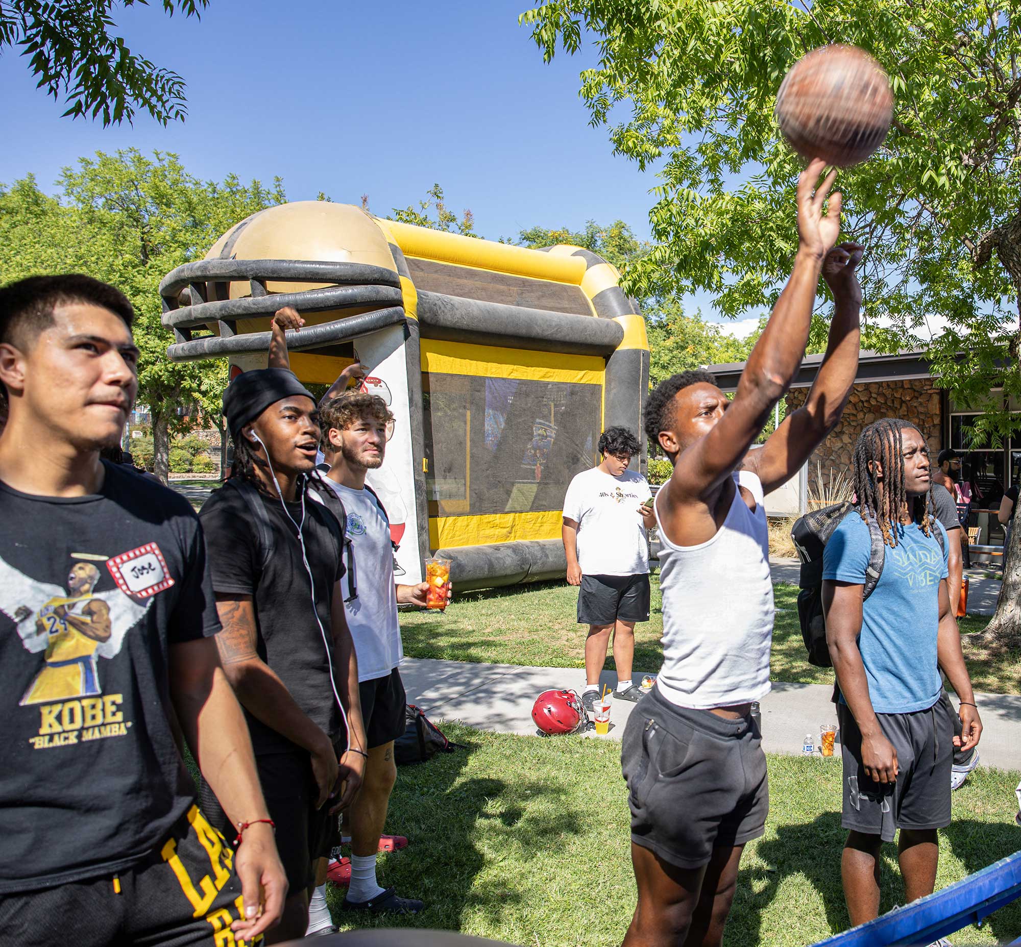 Student attempts to get basketball into a hoop as students look on.