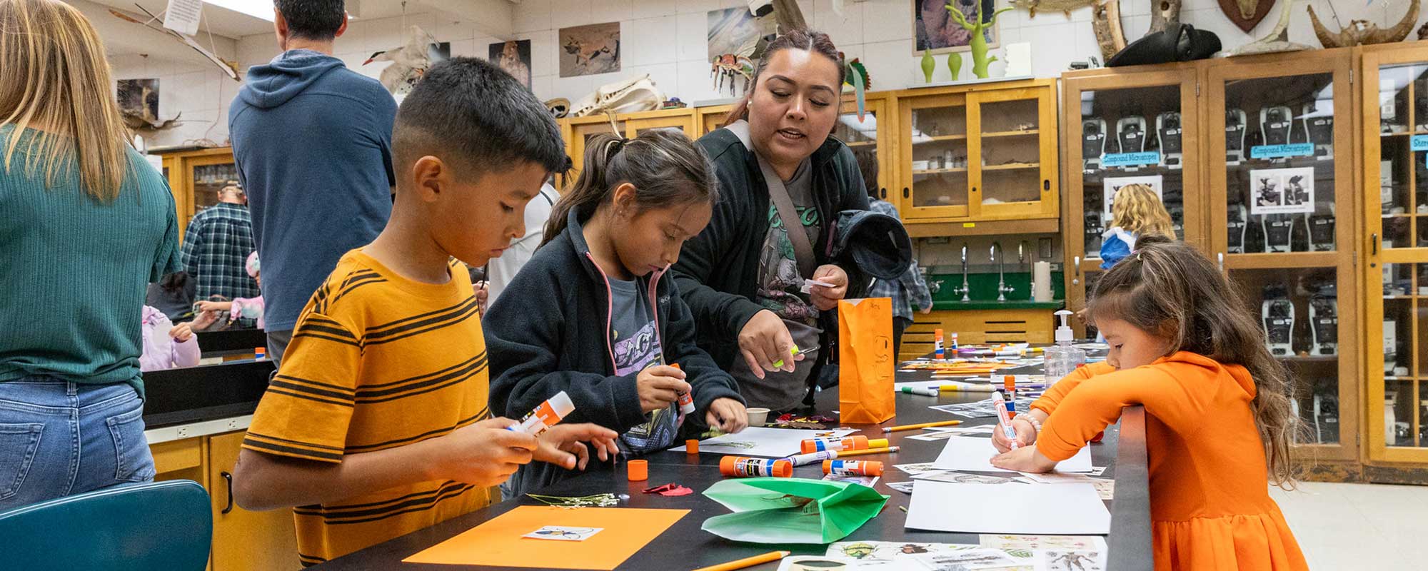 Children in costumer work on science craft at Night at the Booseum