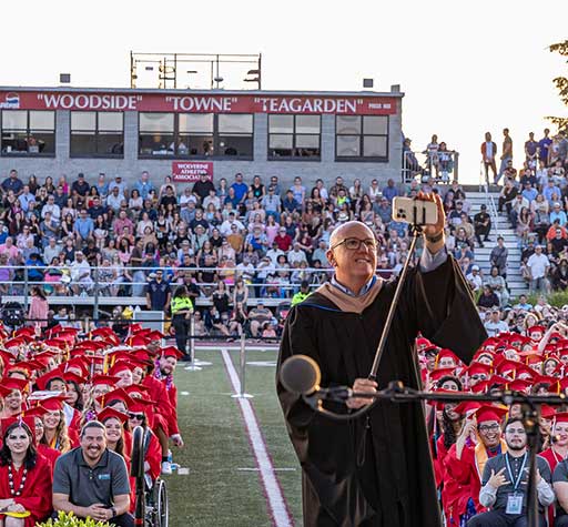 President Willy taking selfie with graduates at commencement