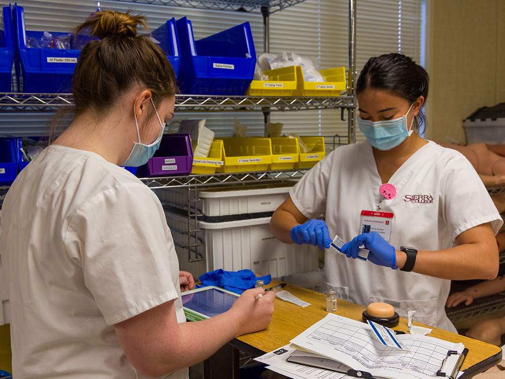 Registered Nursing students practice using sharps and recording patient details into a tablet.